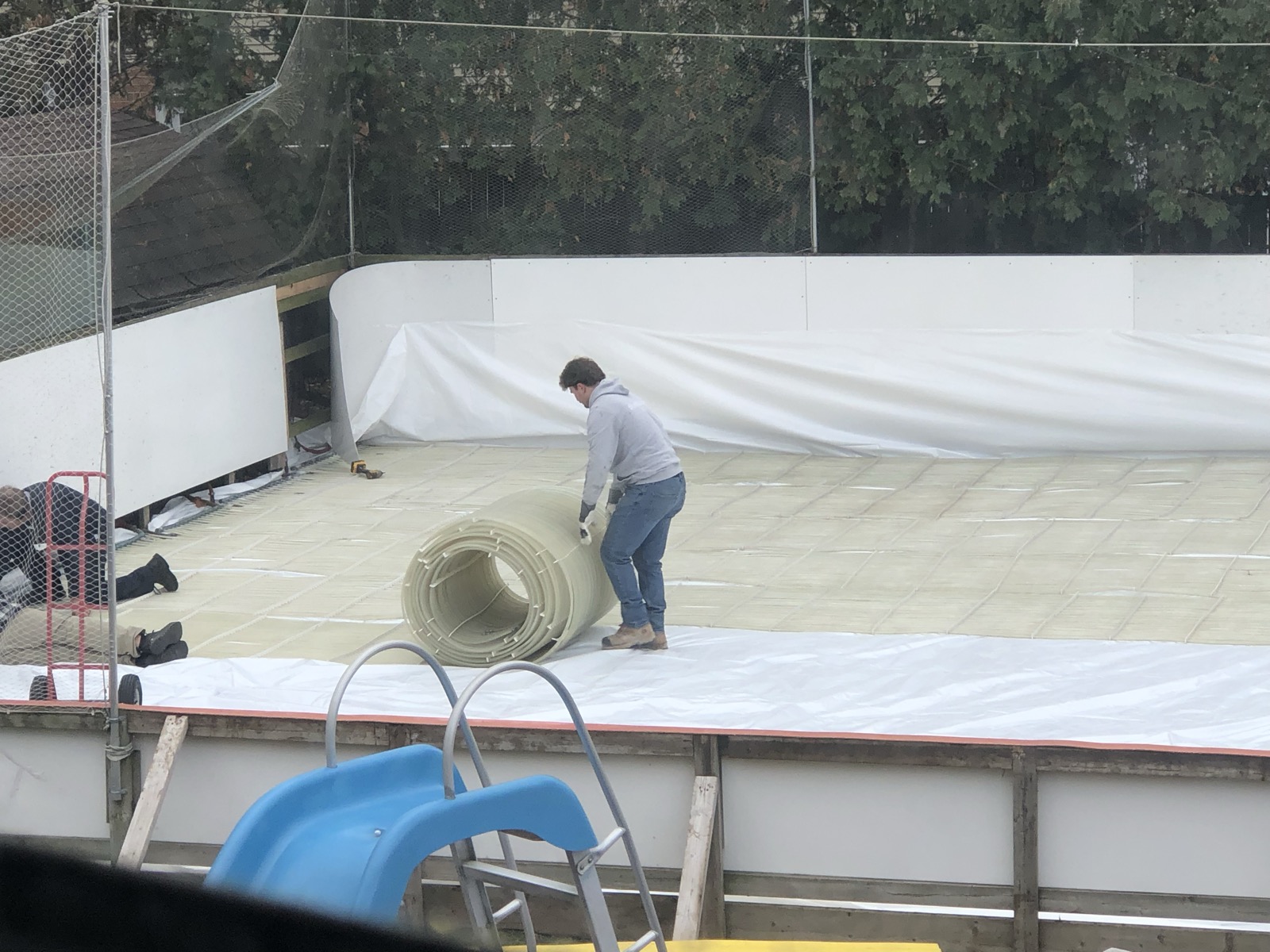 Refrigeration tubing being rolled out across the rink pad